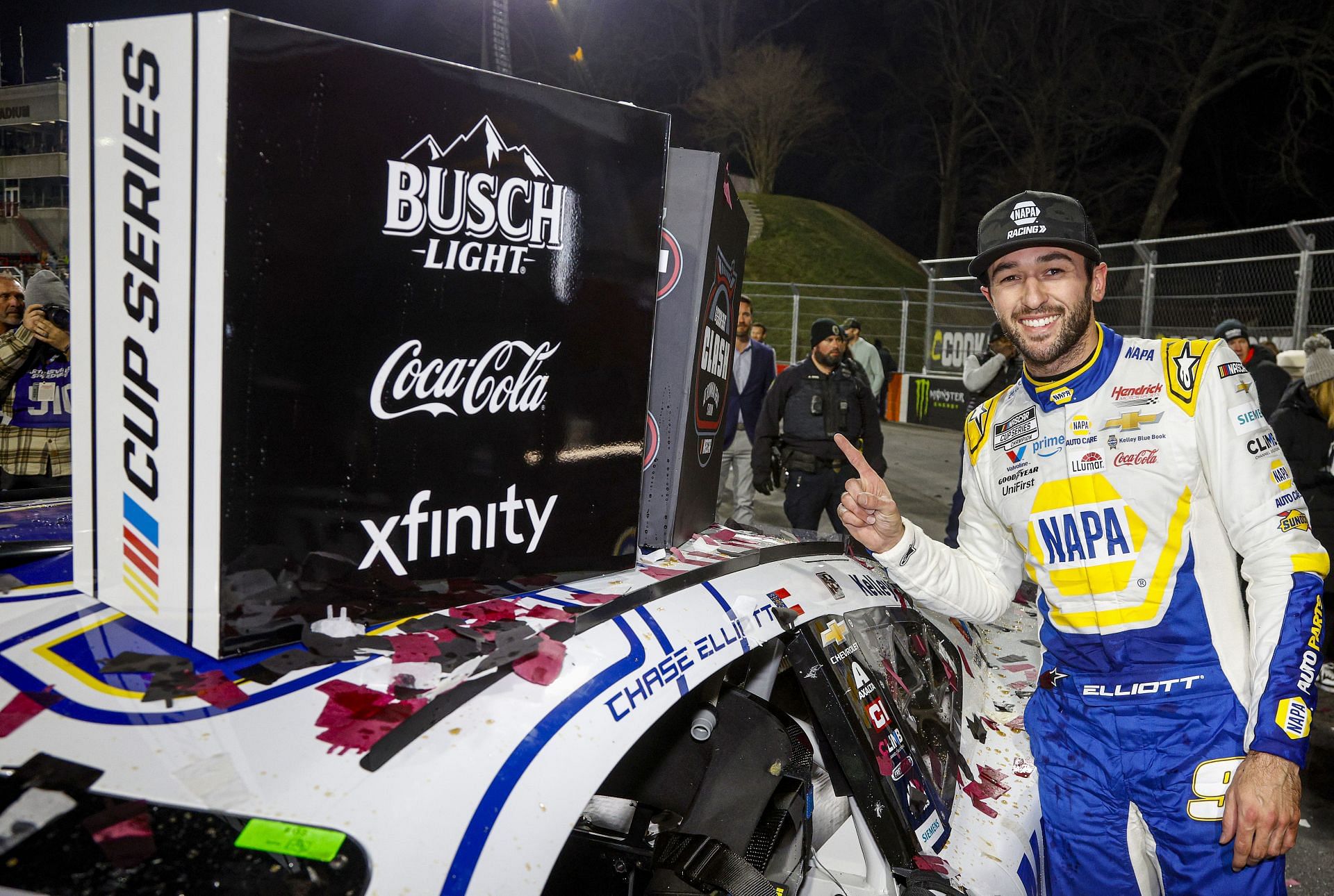 Chase Elliott poses with the winner sticker on his car in victory lane after winning the Cook Out Clash at Bowman Gray Stadium - Source: Getty