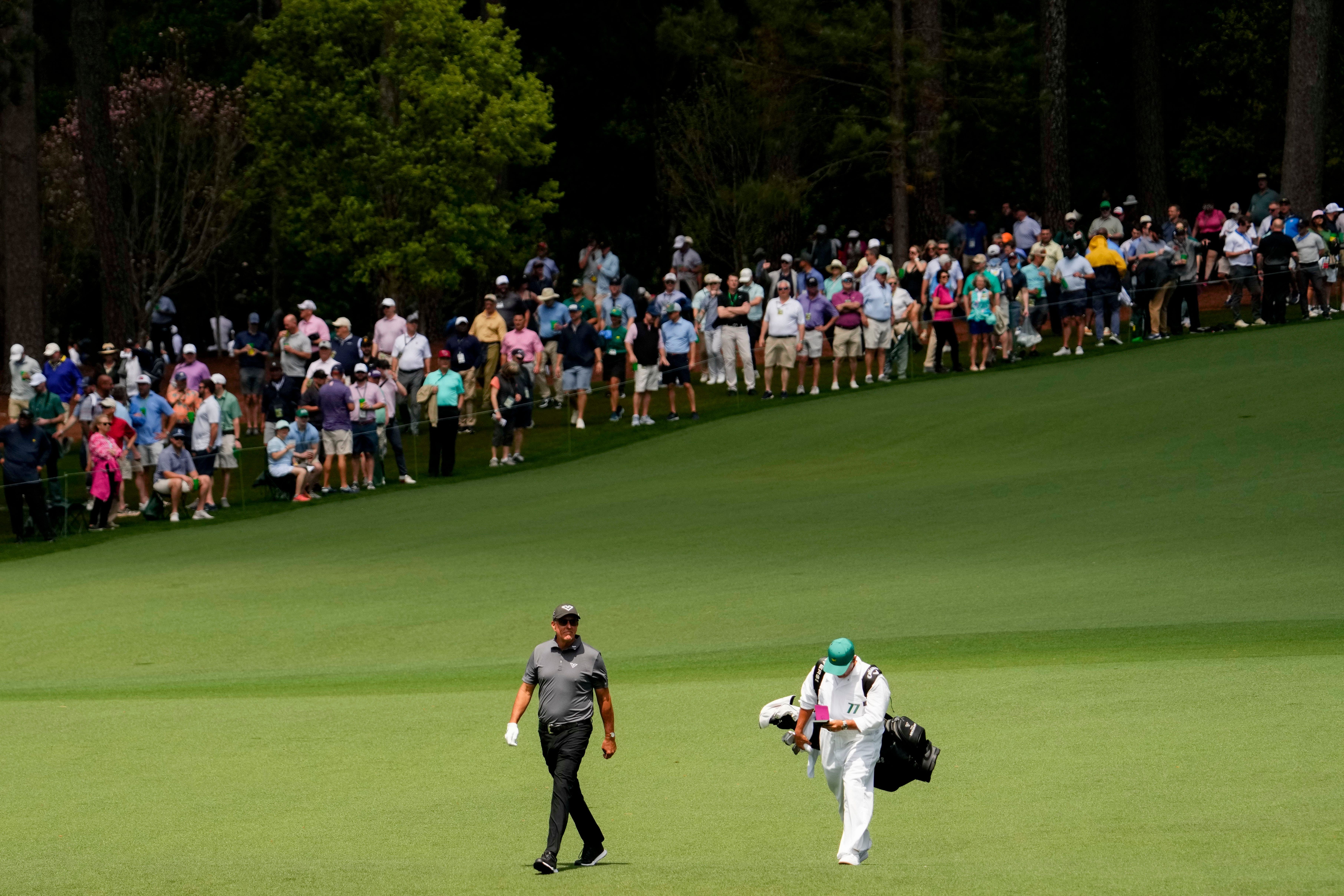 Phil Mickelson walks down the no. 2 fairway with his caddie, Jon Yarbrough, during the first round of the Masters Tournament - Source: Imagn