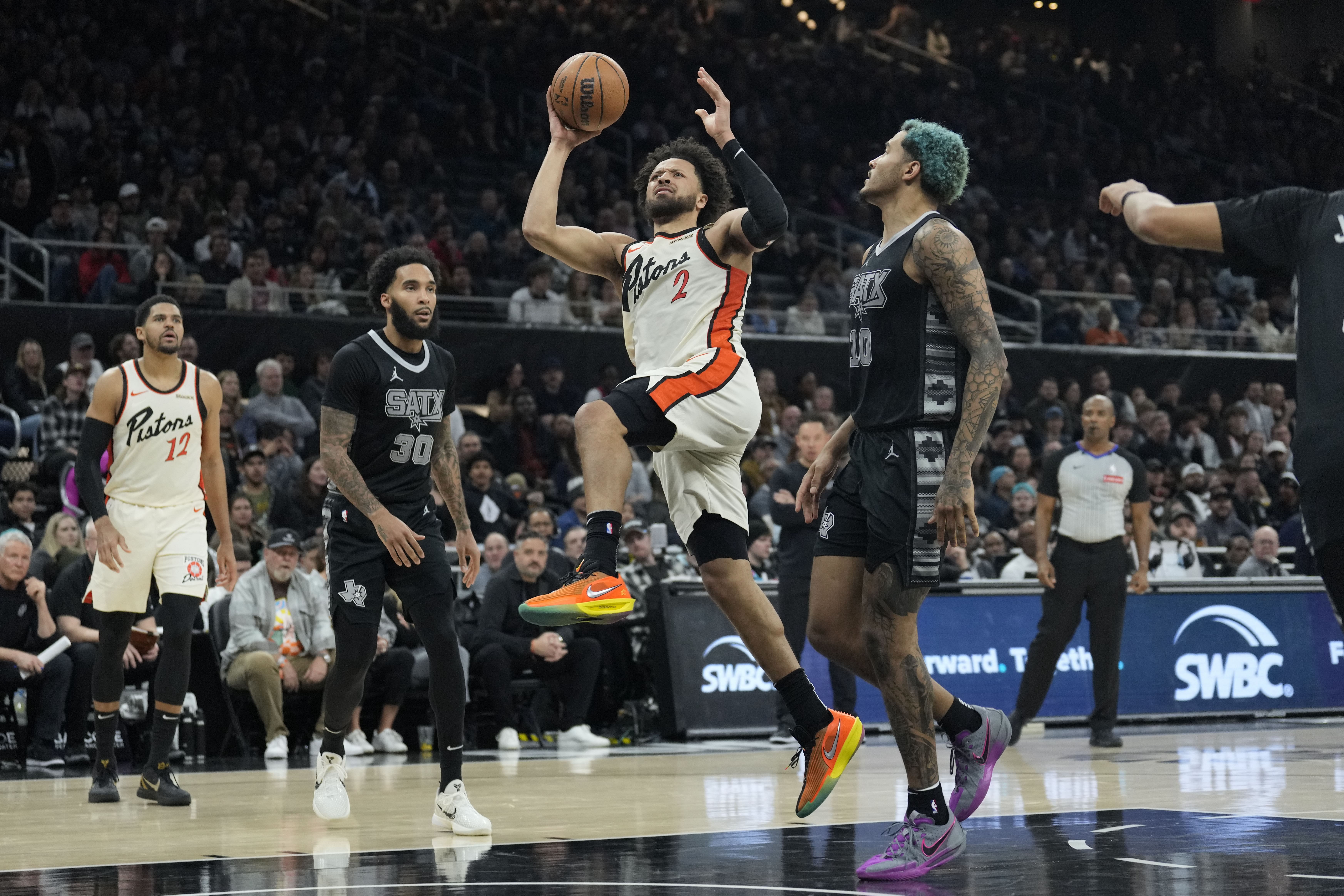 Feb 21, 2025; Austin, Texas, USA; Detroit Pistons guard Cade Cunningham (2) drives to the basket between San Antonio Spurs forwards Jeremy Sochan (10) and Julian Champagnie (30) during the second half at Moody Center. Mandatory Credit: Scott Wachter-Imagn Images - Source: Imagn