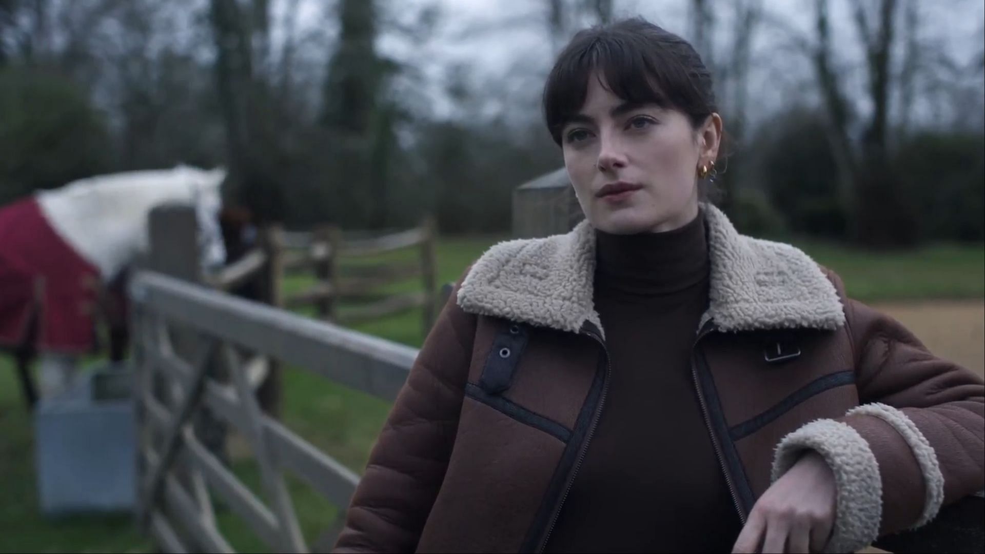 Eliza Huntley (Millie Brady) leans against a fence at the Huntley estate while speaking to Sophie (Image via AppleTV+)