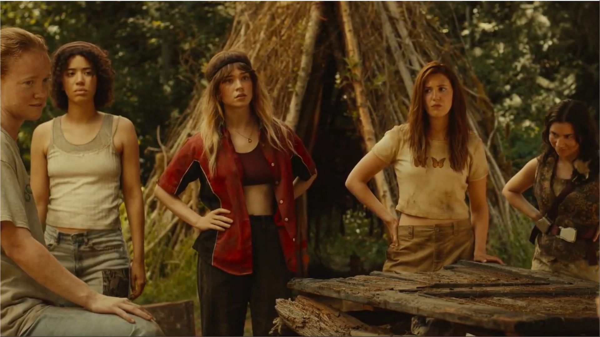 Samantha Hanratty (Misty), Sophie Thatcher (Natalie), and Sophie N&eacute;lisse (Shauna) gather with other survivors near their shelter, reflecting on a critical decision. (Image via Paramount+)