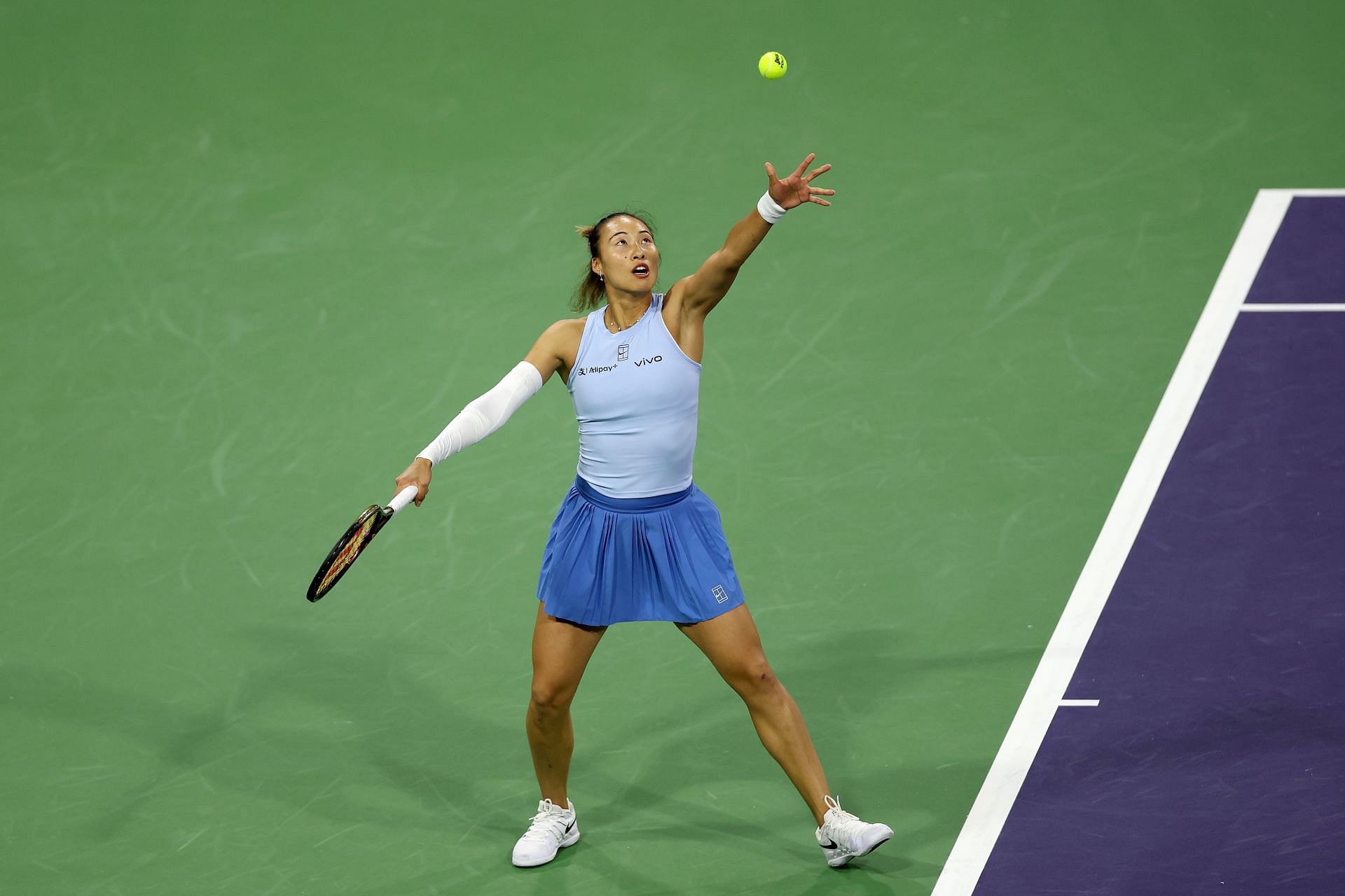 Zheng Qinwen tosses a ball to serve in the BNP Paribas Open - Source: Getty