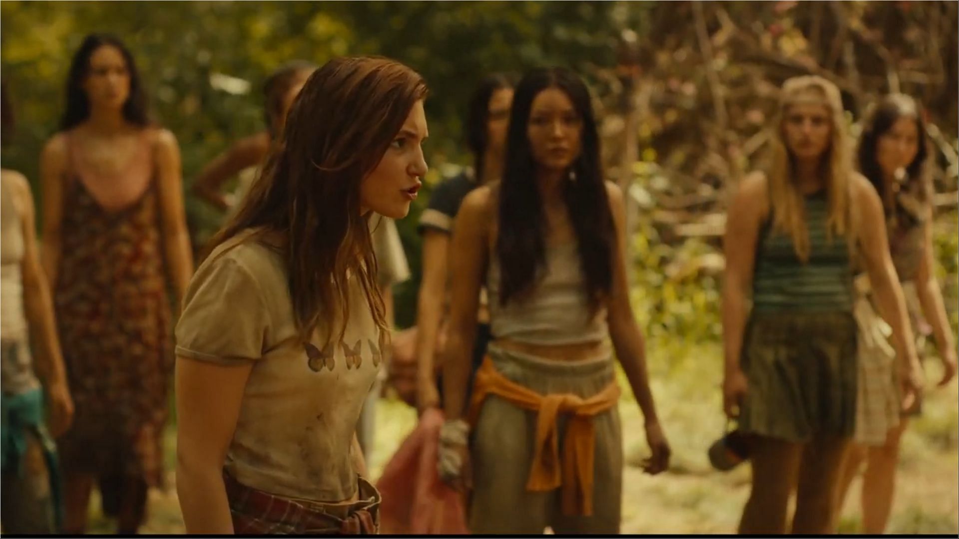 Sophie N&eacute;lisse (Shauna) speaks with authority as the Yellowjackets survivors, including Liv Hewson (Van), Courtney Eaton (Lottie), and Alexa Barajas (Mari), stand behind her in a tense moment. (Image via Paramount+)