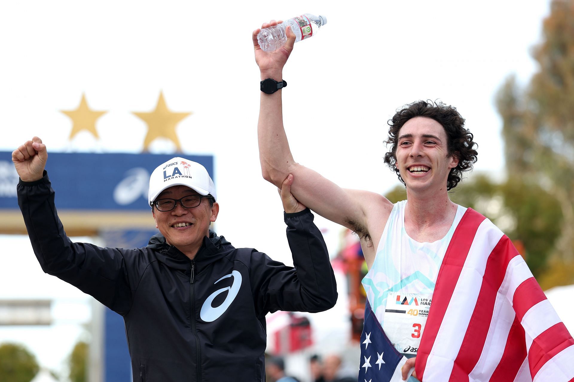 Richtman celebrating his 2025 Los Angeles Marathon victory alongside the CEO and President of Asics America (Image via: Getty Images)