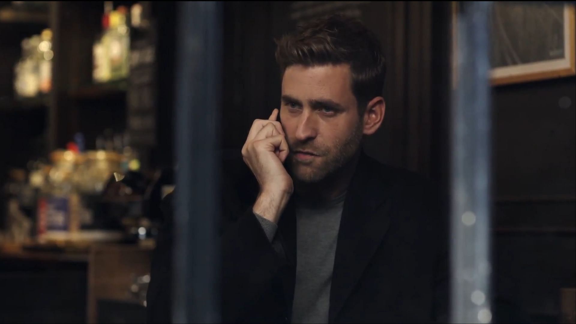 James sits in a dimly lit bar while on a phone call with Sophie. His intense expression suggests he is strategizing his next move in confronting Sophie. (Image via AppleTV+)