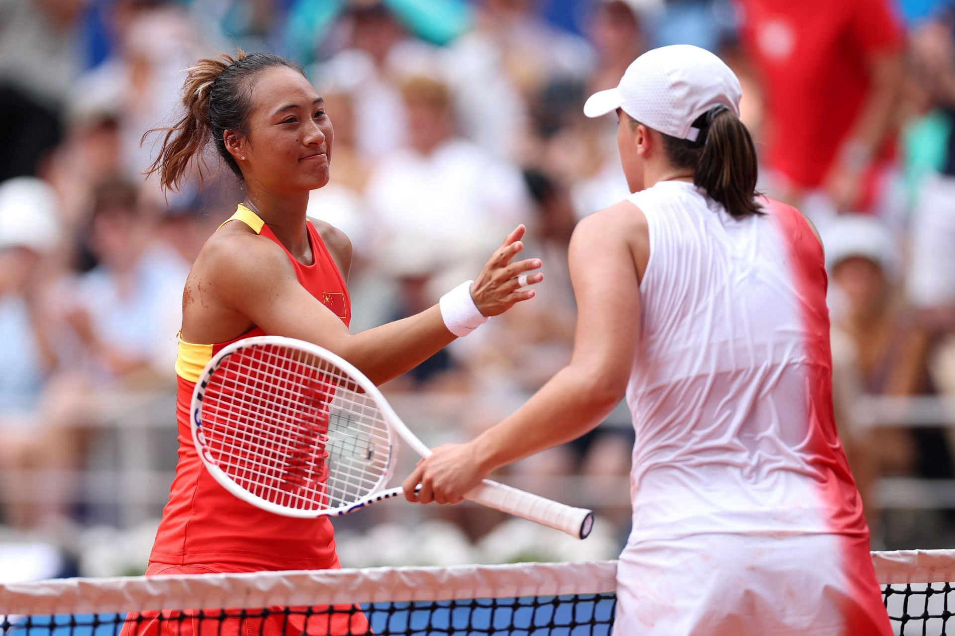 Zheng Qinwen and Iga Swiatek at the net following their Olympics match | Image Source: Getty