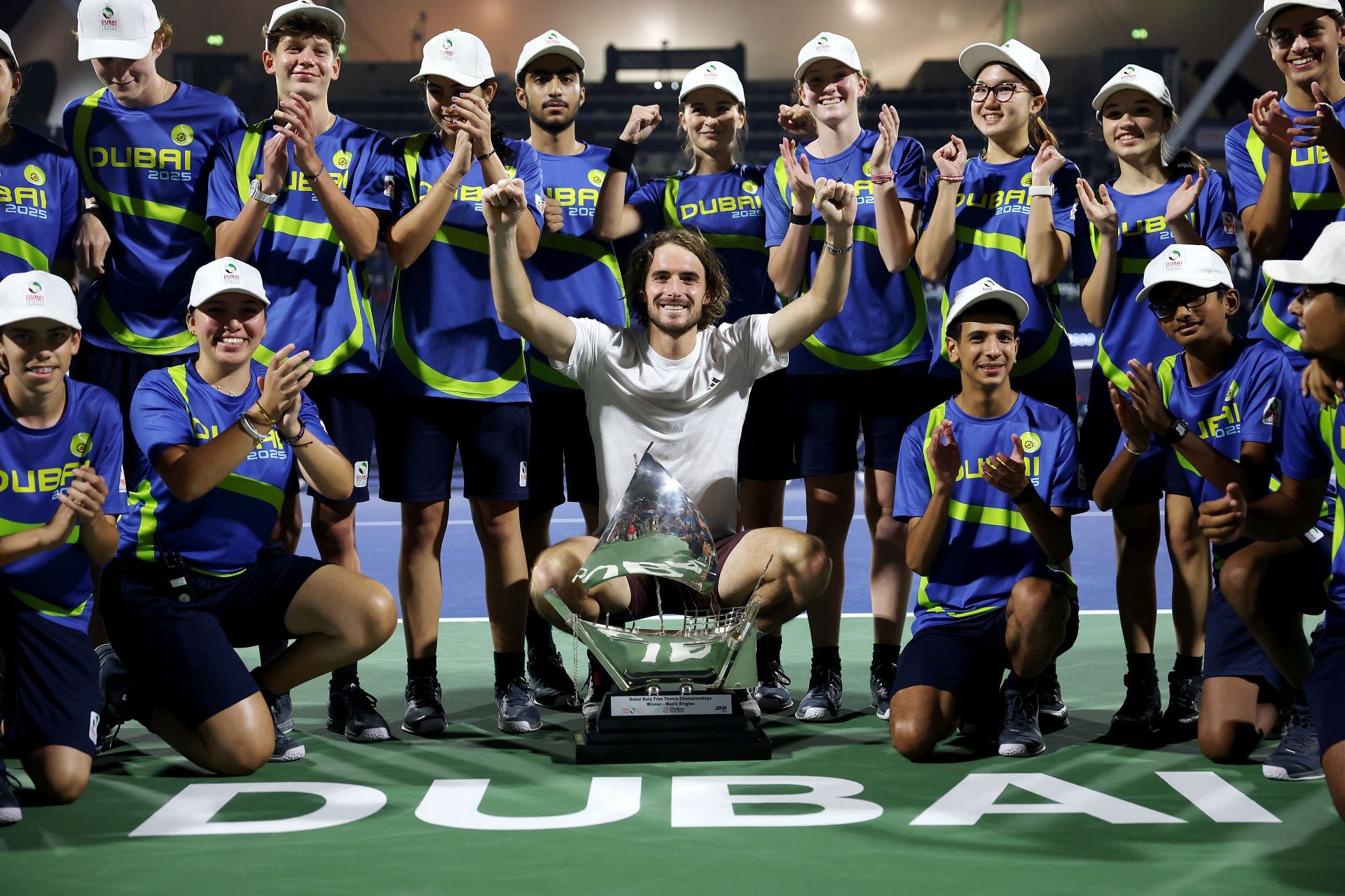 Stefanos Tsitsipas of Greece celebrates with the trophy and ball kids after victory over Felix Auger-Aliassime of Canada in the final during day fourteen of the Dubai Duty Free Tennis Championships - Source: Getty