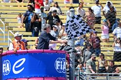 Damon Hill reacts to Guenther Steiner's clumsy moment while waving the checkered flag during a Formula E race