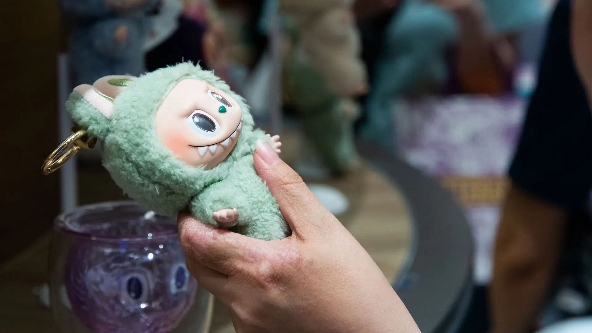 A shopper holds a Labubu doll as people line up for the special Labubu convenience store edition sale (Image via Getty)