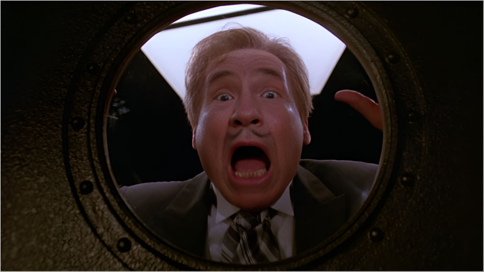 Mel Brooks as President Skroob looking shocked through a porthole window in a scene from Spaceballs.
