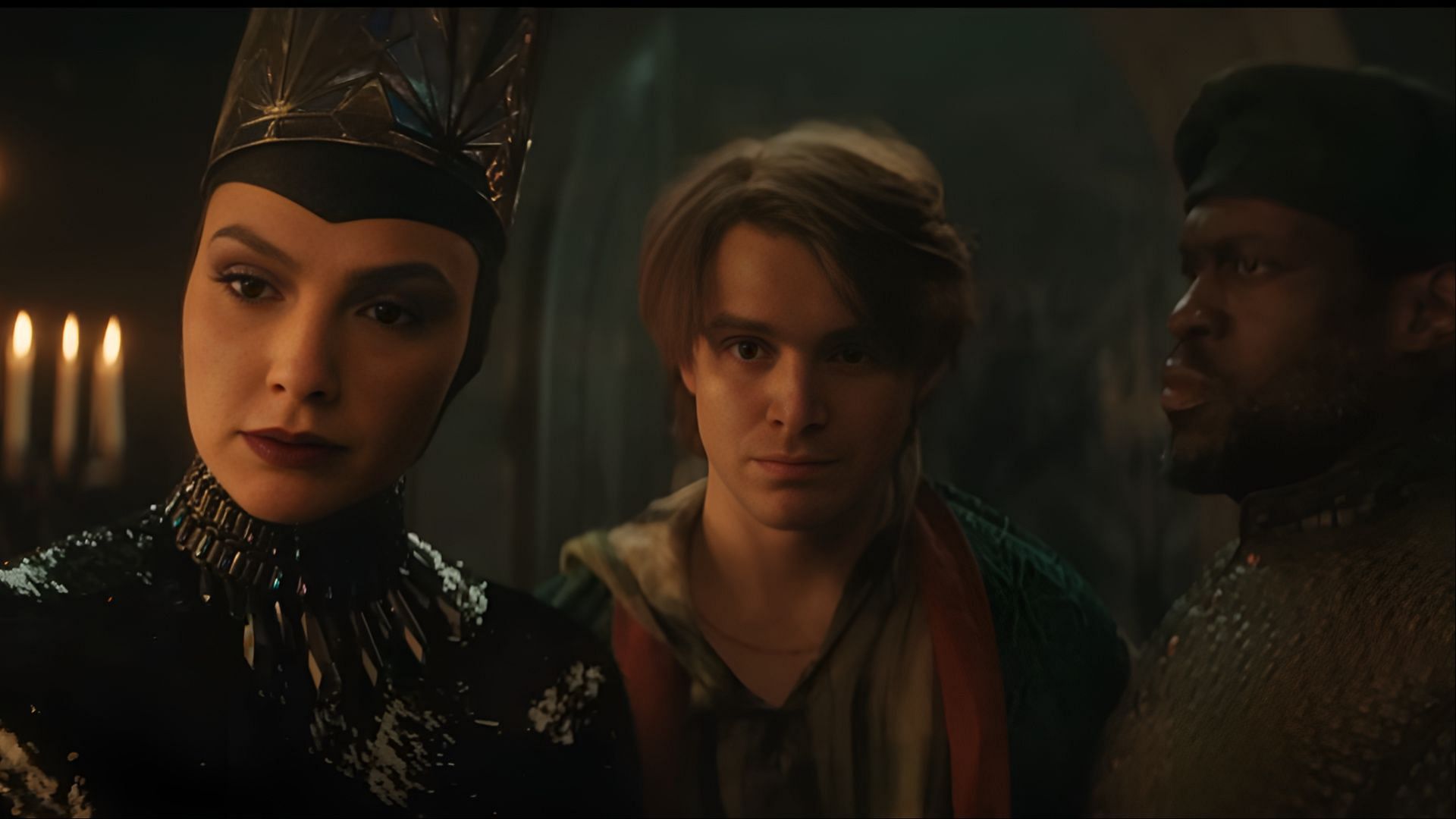 Gal Gadot as the Evil Queen alongside Andrew Burnap and another supporting character in a dramatic scene from the film. (Image via Disney)