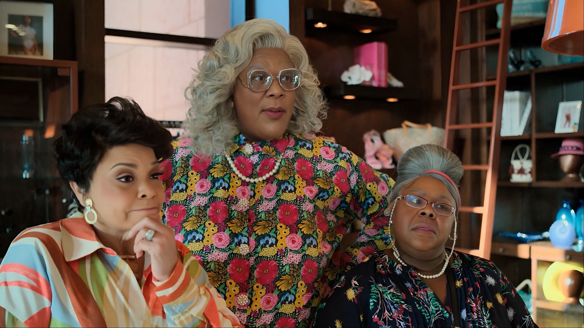 Tyler Perry as Madea, Tamela Mann as Cora, and Cassi Davis Patton as Aunt Bam standing together inside a resort suite in Madea&rsquo;s Destination Wedding, wearing colorful outfits and serious expressions