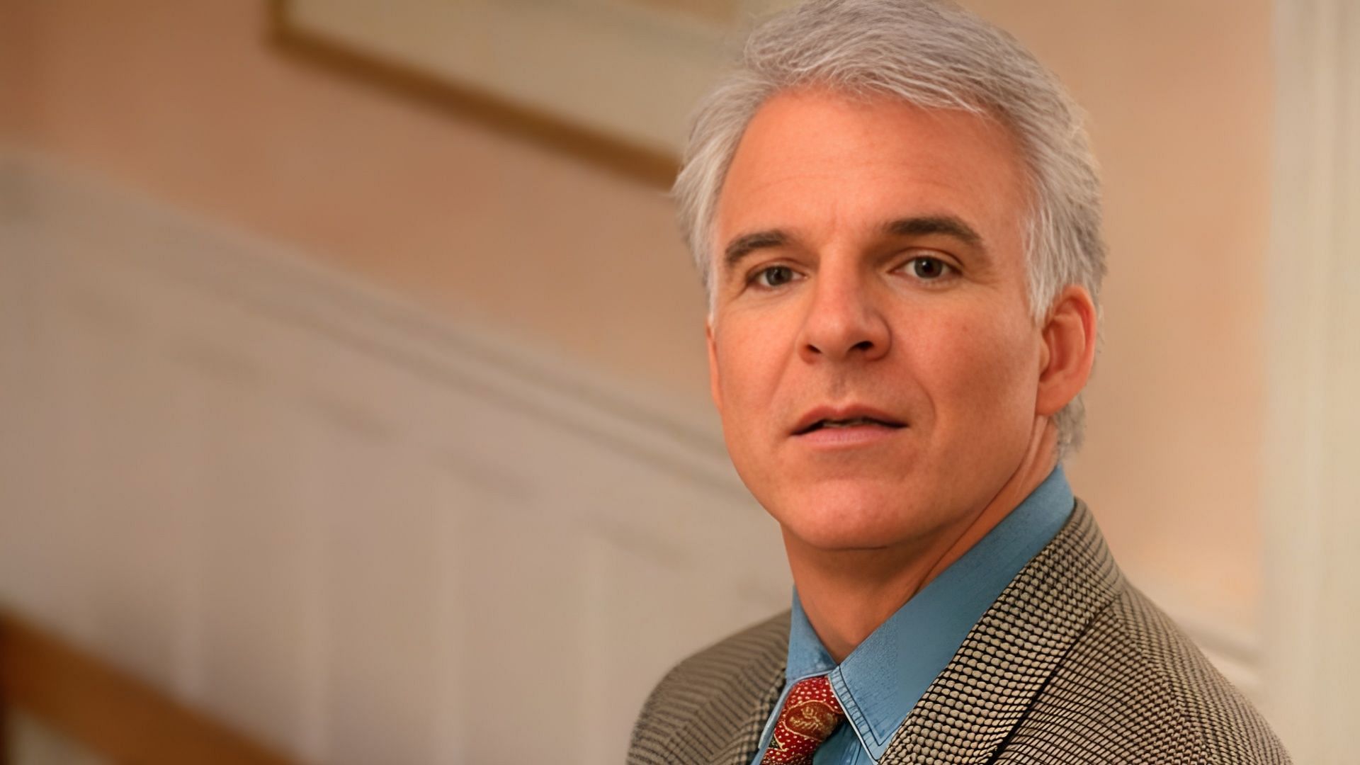 Steve Martin in a checked jacket and tie, looking directly at the camera in a still from Father of the Bride.