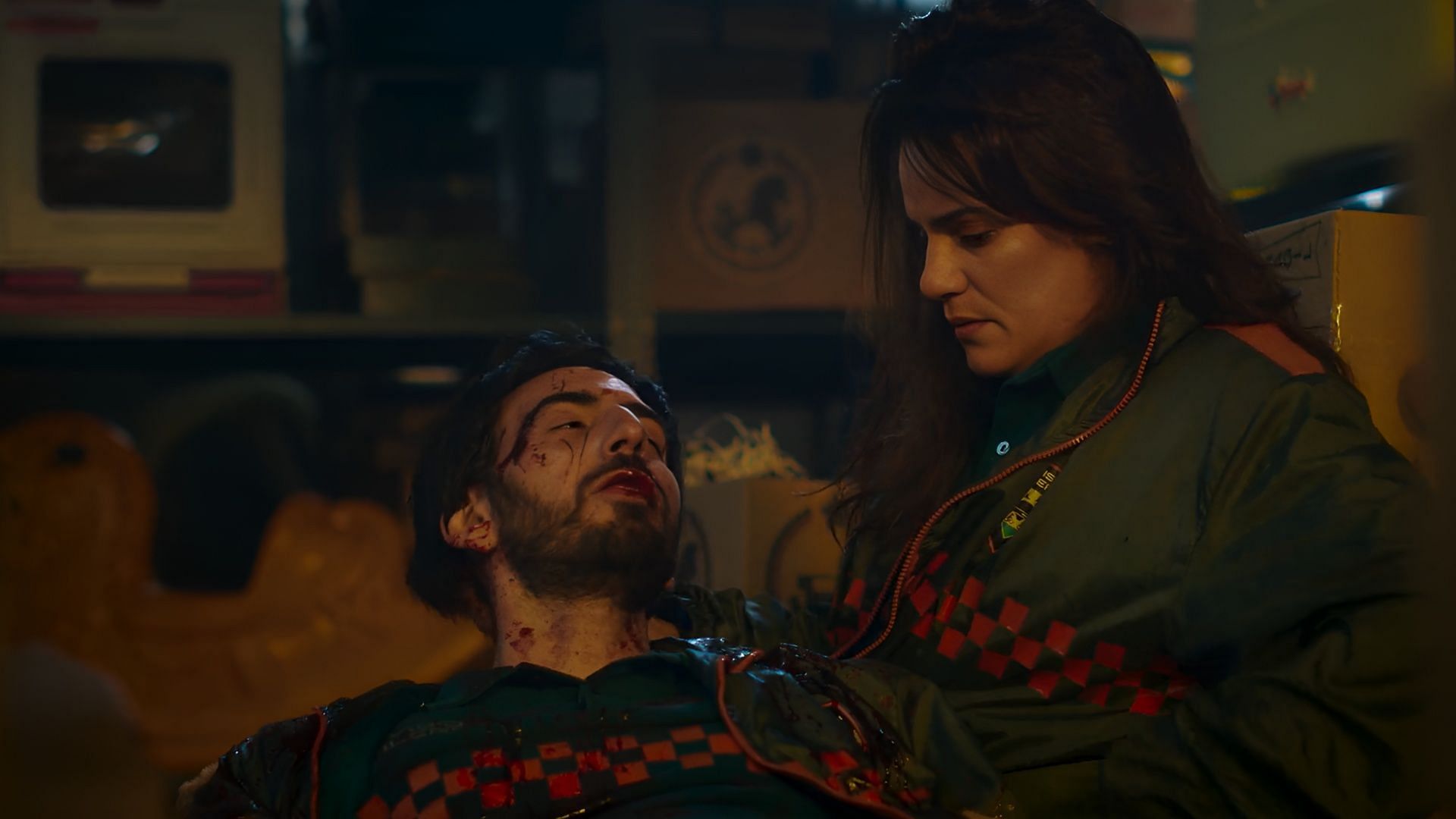 Sofia holding an injured Felipe on the warehouse floor in an emotional scene from Community Squad season 1.