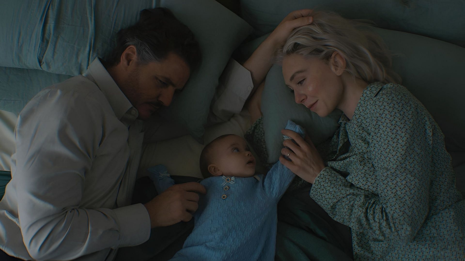 Reed Richards and Sue Storm lying in bed with baby Franklin between them, sharing an intimate family moment from Fantastic Four: First Steps.