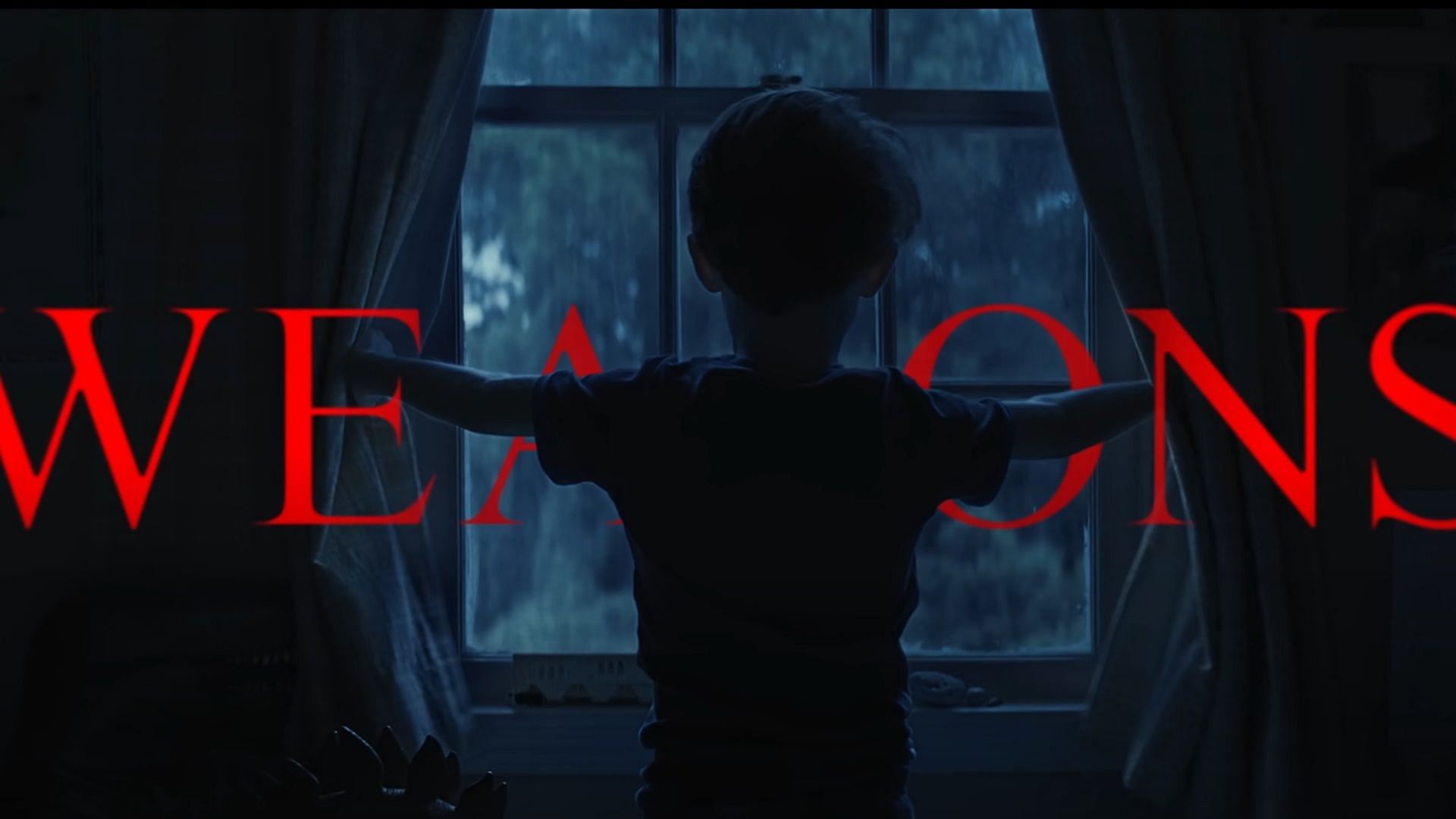 A backlit child opens curtains in a dimly lit room with the word &ldquo;WEAPONS&rdquo; in bold red overlaying the image. This is the title card from the trailer of Weapons 2025.