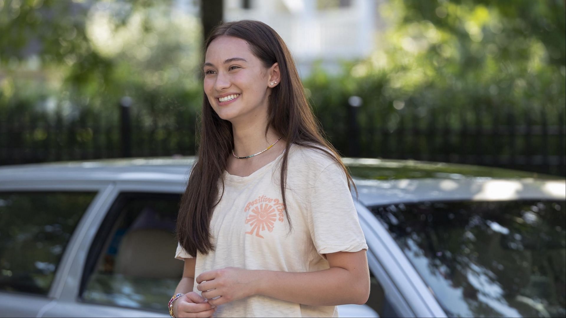Belly smiling while standing outdoors in a casual outfit in The Summer I Turned Pretty season 3.