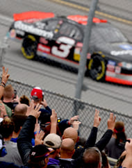 Fans hold up three fingers as Earnhardt Sr.'s No. 3 drives past at Talladega Superspeedway. Source: Imagn