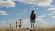 A scene from East of Wall filmed near Wall, South Dakota, showing a character standing by handmade wooden crosses in a rural cemetery (Image via Sony Pictures)