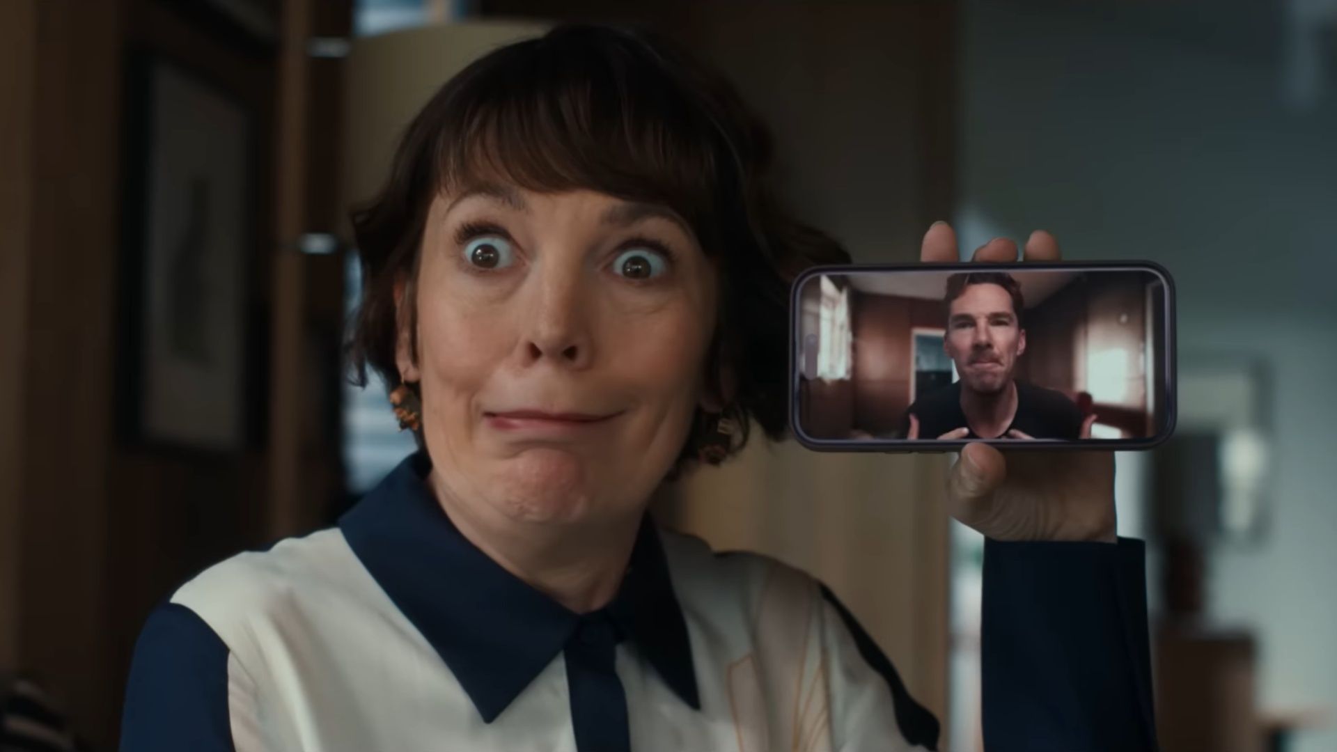 The Roses blends humour and chaos as Ivy holds up Theo&rsquo;s video call, masking tension with comedy before the marriage unravels. (Image via YouTube/Searchlight Pictures) b
