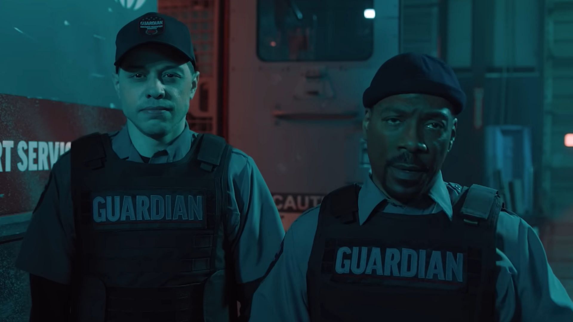 Travis Stolly and Russell Pierce wear tactical gear while standing near an armored vehicle.