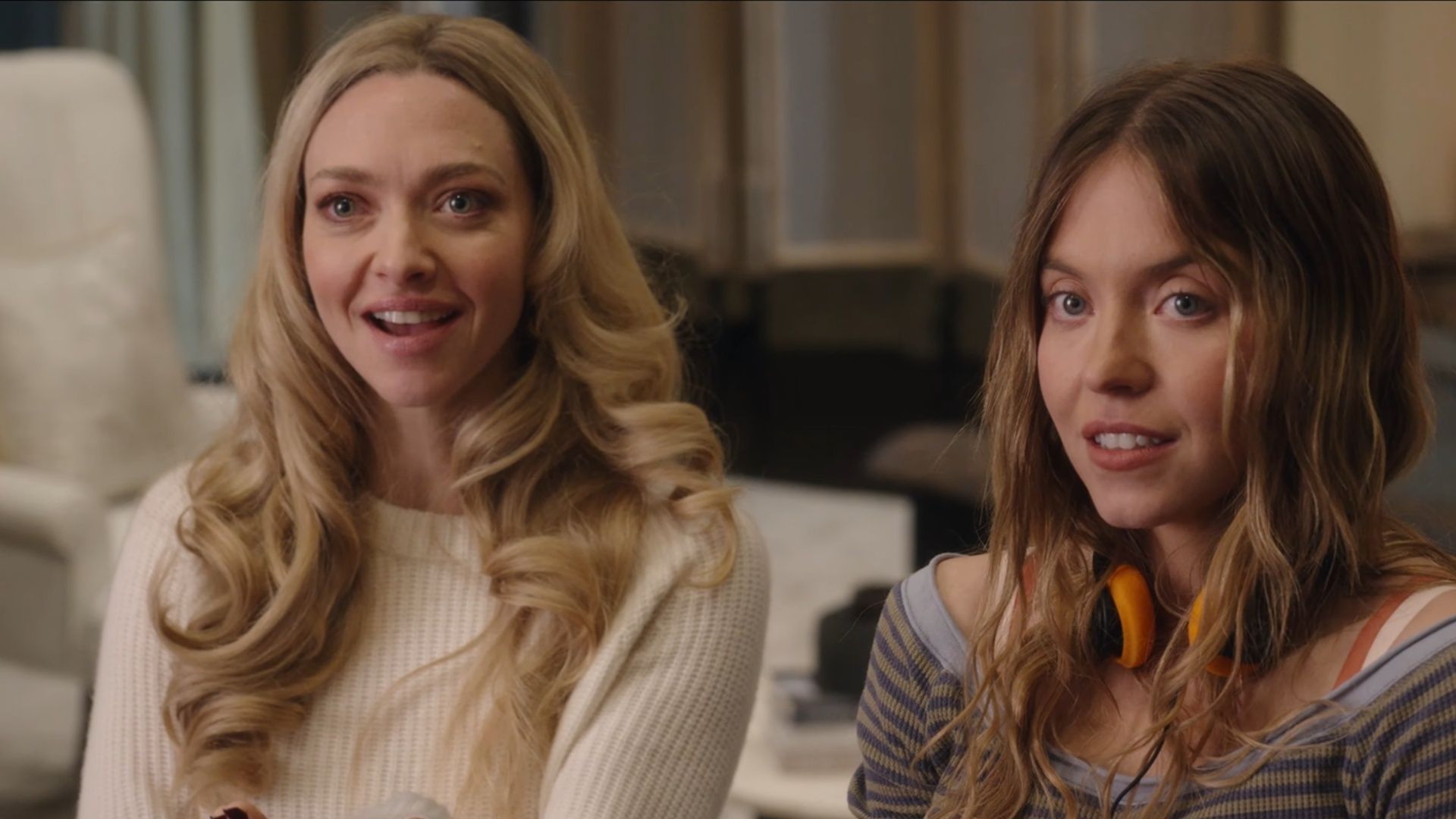 Sydney Sweeney and Amanda Seyfried sit together in a scene from The Housemaid, appearing as their characters Millie Calloway and Nina Winchester.