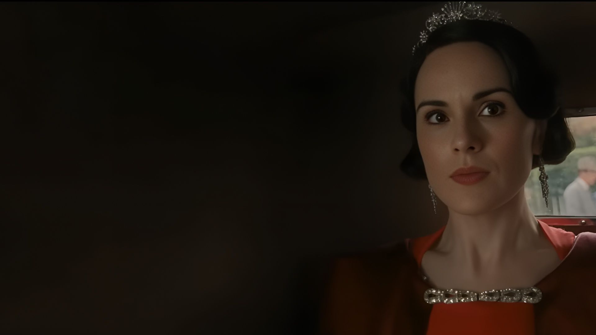 Close-up of Lady Mary Crawley (Michelle Dockery) wearing a tiara and earrings while seated indoors in Downton Abbey: The Grand Finale.