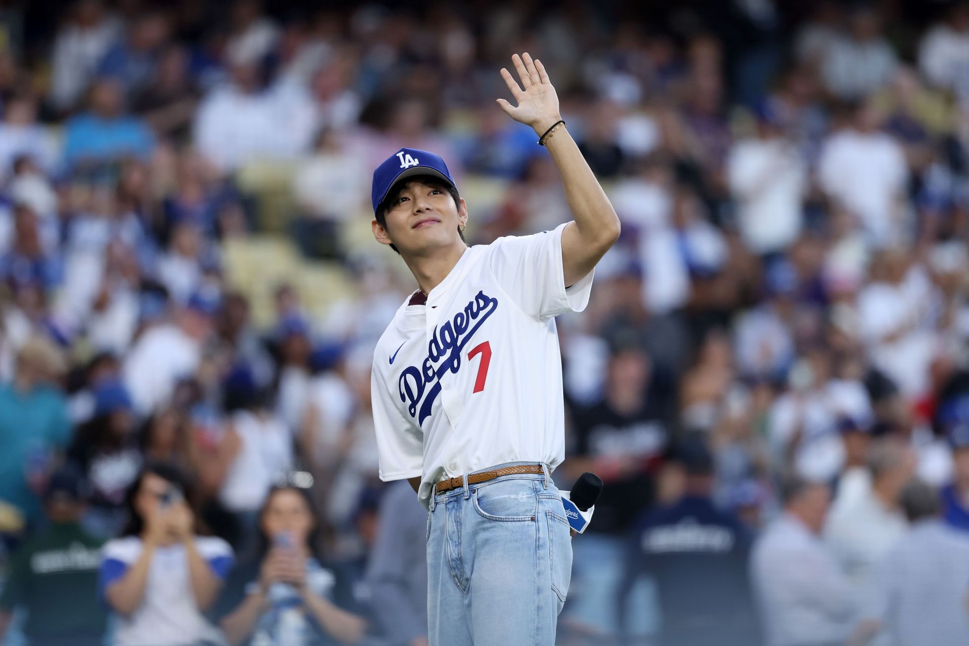 V of BTS acknowledges the crowd before the game between the Los Angeles Dodgers and the Cincinnati Reds at Dodger Stadium on August 25, 2025 (Image via Getty)