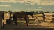 The young girl reaches out to a horse in a quiet moment that contrasts innocence and danger in Killing Faith. (Image via Shout! Studio)