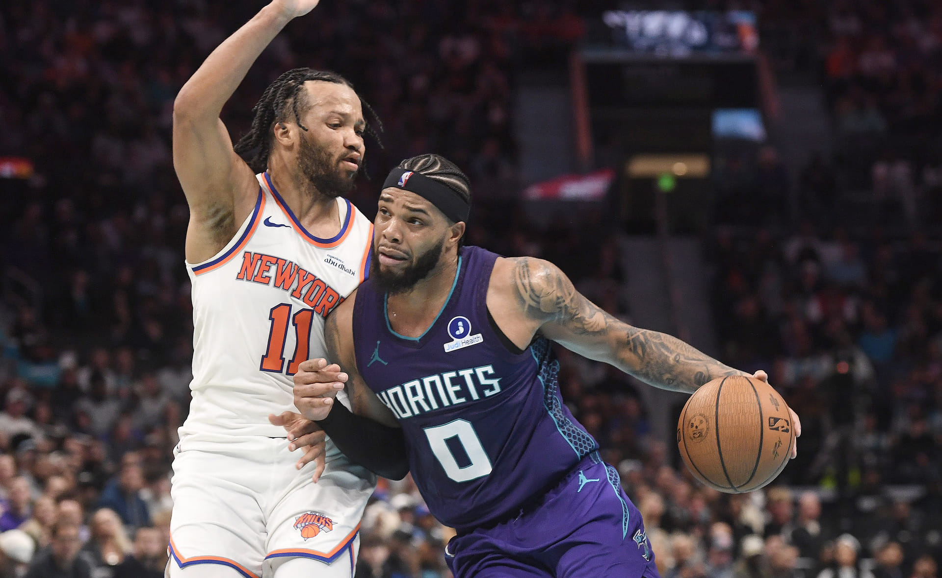 Nov 26, 2025; Charlotte, North Carolina, USA; Charlotte Hornets forward Miles Bridges (0) drives past New York Knicks guard Jalen Brunson (11) during the second half at the Spectrum Center. Mandatory Credit: Sam Sharpe-Imagn Images