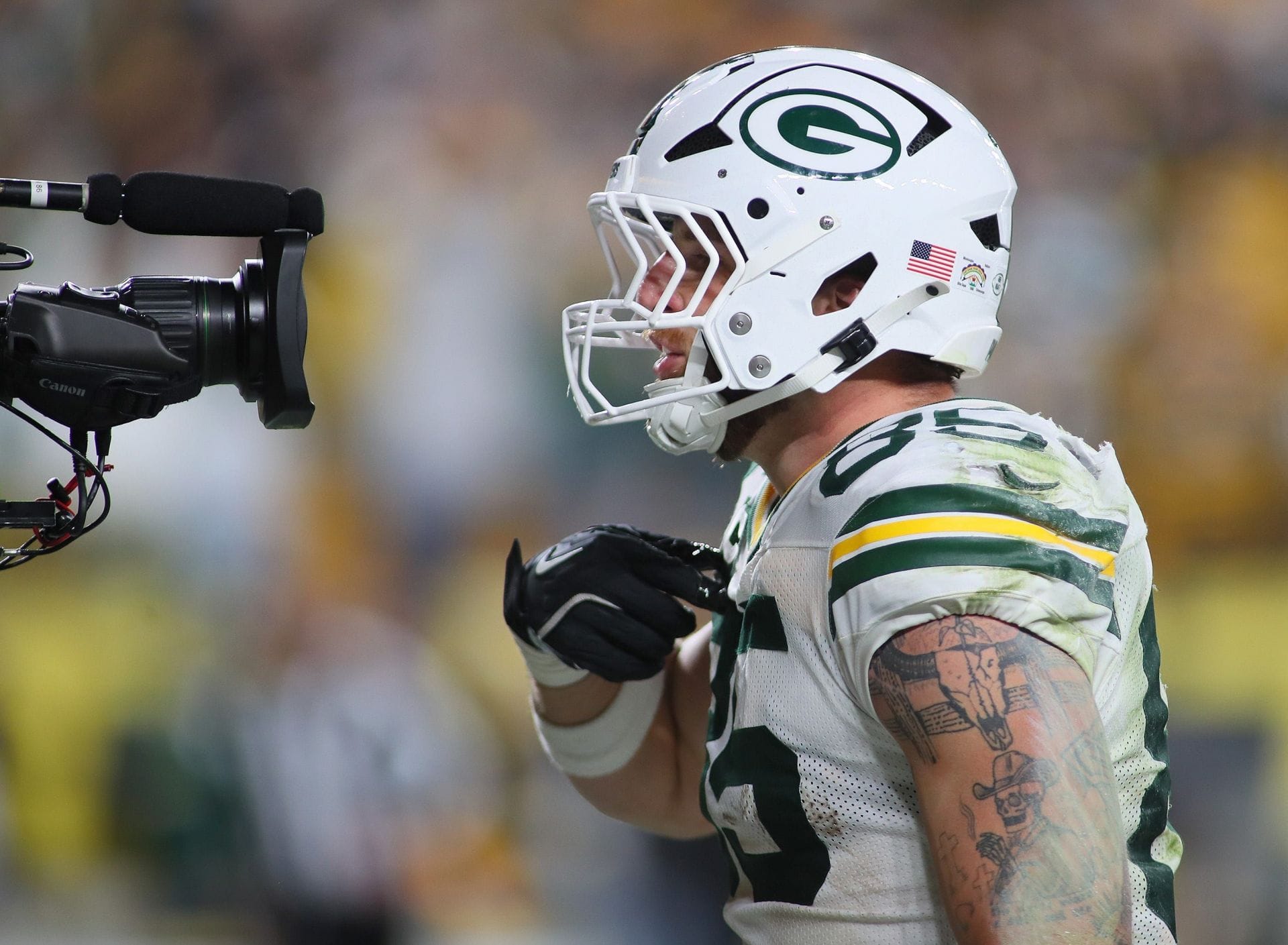 O tight end do Green Bay Packers, Tucker Kraft, fala para a câmera após marcar um touchdown. - Fonte: Imagem