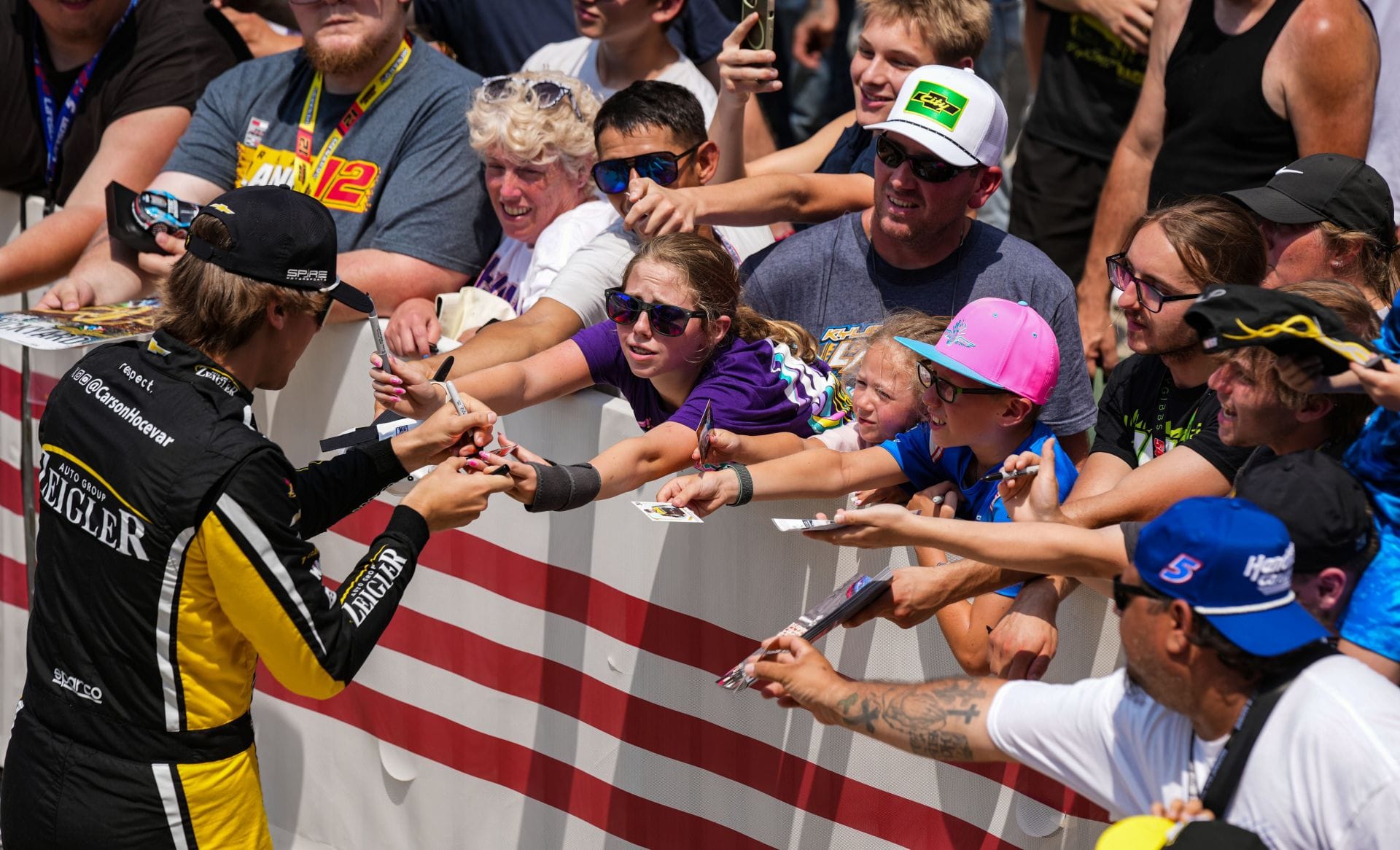 Racing fans reach for NASCAR Cup Series driver Carson Hocevar for an autograph at Indianapolis Motor Speedway. - Source: Imagn