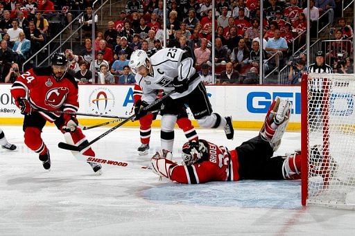 Los Angeles Kings&#039; Dustin Brown (R) goes for a loose puck as New Jersey Devils goaltender Martin Brodeur defends