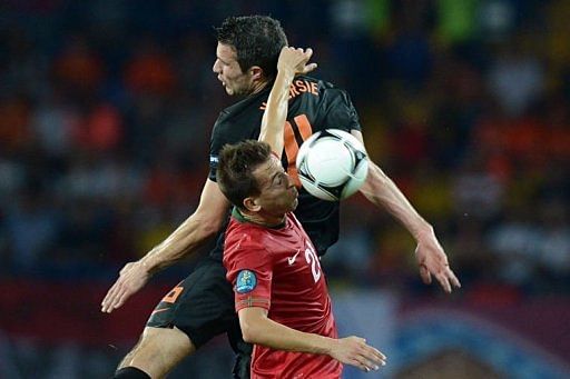 Dutch forward Robin van Persie (back) and Portuguese defender Joao Pereira jump for a header