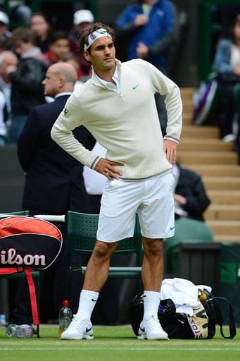 Roger Federer keeps warm during a delay