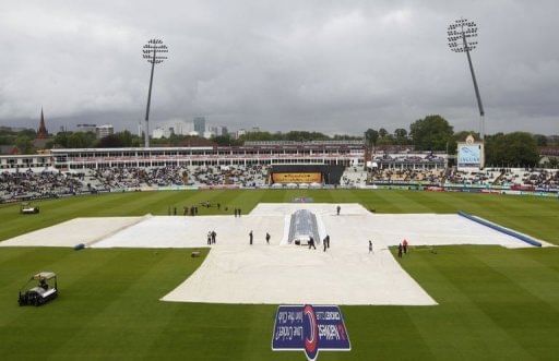 Groundstaff cover the pitch as rain delays the start