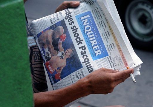 A man reads a newspaper showing Philippine boxing superstar Manny Pacquiao&#039;s title bout in Manila