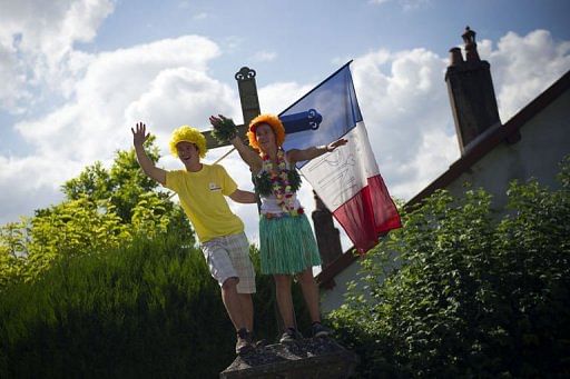 Fans wave a French flag as they wait for riders