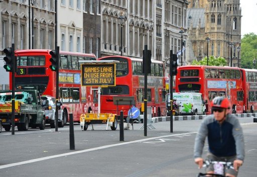 Buses pass by a sign advising that lanes will be reserved to Olympic transport