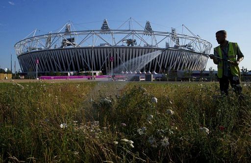 A gardener waters a patch of flowers near the Olympic stadium at the Olympic Park in London