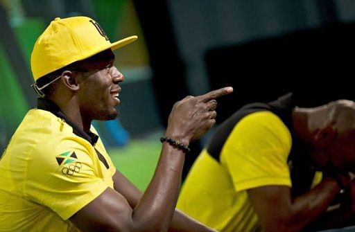 Usain Bolt points to a reporter while teammate Asafa Powell (R) bursts into laughter during a press conference