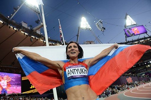 Russia&#039;s Natalya Antyukh holds her national flag as she celebrates winning the women&#039;s 400m hurdles final