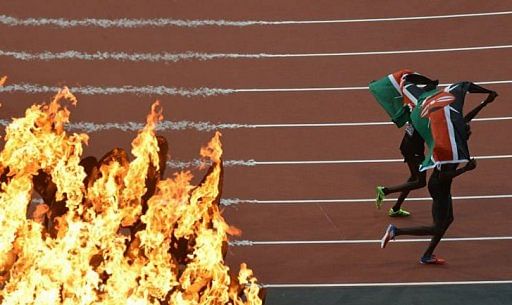 The Olympic torch is seen as Kenya&#039;s David Lekuta Rudisha and Kenya&#039;s Timothy Kitum celebrate after the men&#039;s 800m final