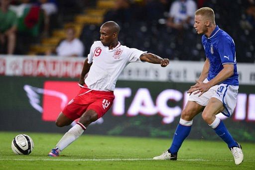 England&#039;s forward Jermain Defoe (L) kicks the ball next to Italian defender Ignazio Abate to score