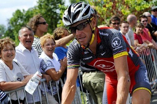 Fans look at Armstrong riding to the signature ceremony prior to the start of the 2010 Tour de France