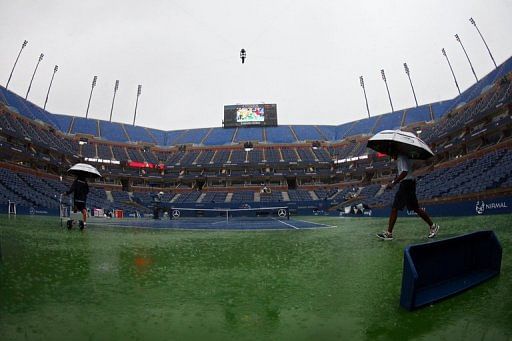 Groundstaff walk on court as the rain pours down interrupting play during Day One of the 2012 US Open