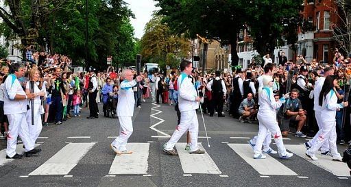 Torchbearers cross Abbey Road with the Paralympic flame as it makes its way towards Olympic Park