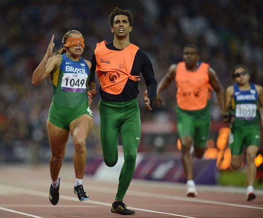 Brazil&#039;s Terezinha Guilhermina (L) runs with her guide Guilherme Soares de Santana to win the Women&#039;s 200 metres T11