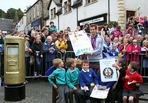 Scottish tennis player Andy Murray (C) poses with local children next to Royal Mail golden post box