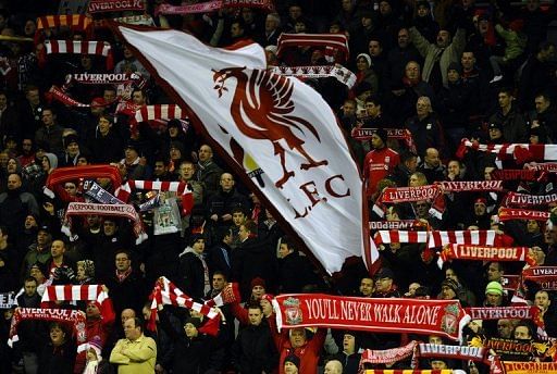Liverpool supporters hold scarves and a flag ahead of a game at Anfield in 2010